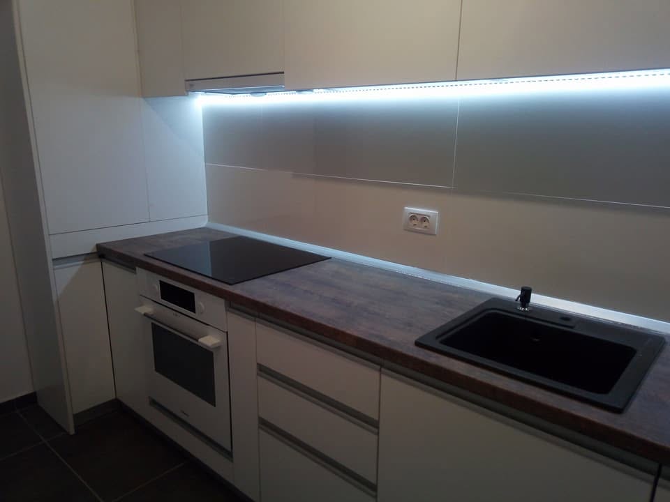 Zona de lucru cu plită, cuptor și chiuvetă neagră. Lucrare Mobi Design în București.